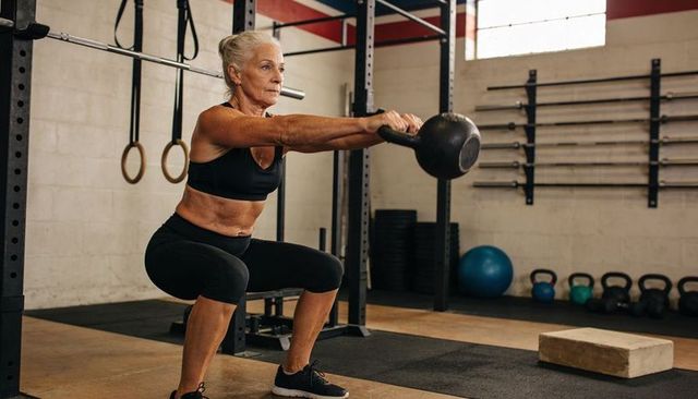 Senior woman performing kettlebell squat building strength, mobility and confidence