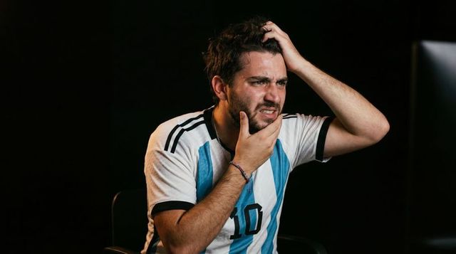 Frustrated soccer fan wearing number 10 jersey reacting to match on screen