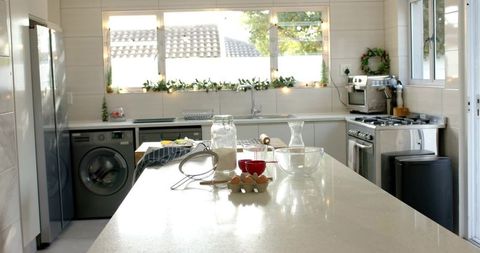 Bright modern kitchen island with baking ingredients, flour jar, eggs and glass bowls