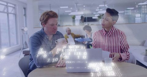 Colleagues Analyzing Data on Laptop in Contemporary Office Environment