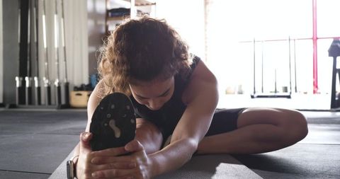 Woman Stretching on Gym Mat in Minimalist Gym Environment