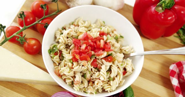 Delicious pasta salad featuring fresh tomatoes, bell peppers, and chopped herbs, perfect for a healthy lunch or dinner. Ideal for blogs and articles promoting healthy eating, websites focused on vegetarian recipes, or meal prep guides. Can also be used in advertisements for restaurants or fresh produce markets.