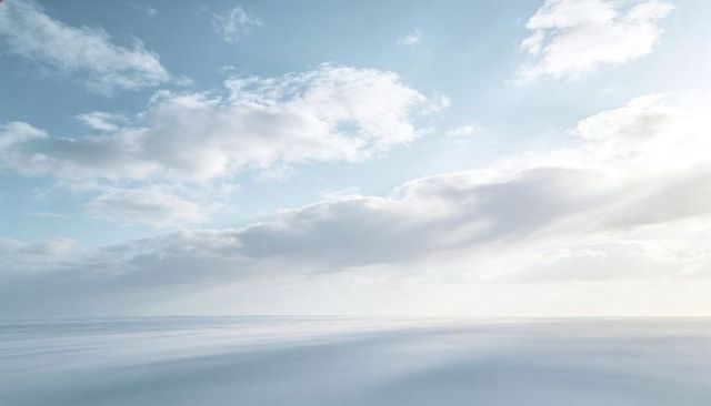 Minimalist pastel seascape with calm reflective ocean and expansive cloud sky
