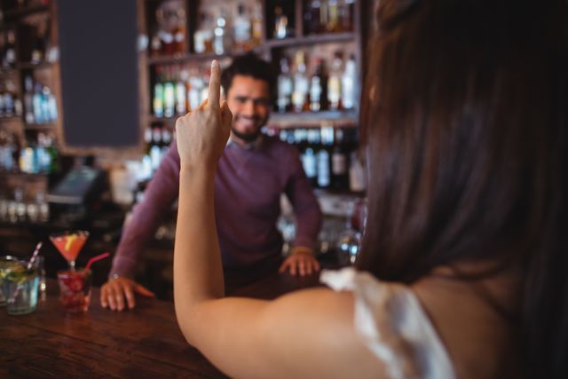 Woman asking for a drink to bar tender at pub