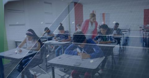 Teacher supervising students taking exam in modern classroom with calculators