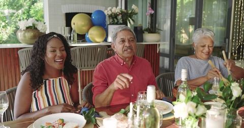 Multigenerational Family Celebrating Outdoors Around Festive Dinner Table with Balloons