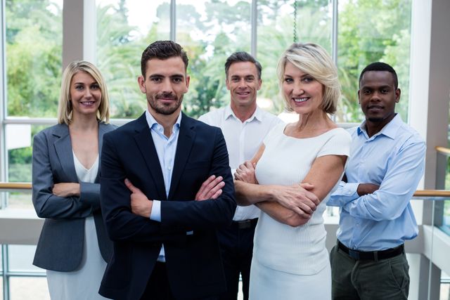 Group of business executives standing with arms crossed in a modern conference center. Ideal for use in corporate presentations, business websites, team-building materials, and promotional content showcasing professional teamwork and leadership.
