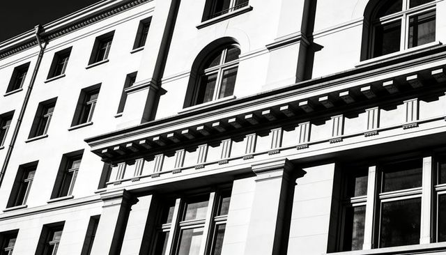 Monochrome classical building facade with arched and sash windows, cornice, pilasters