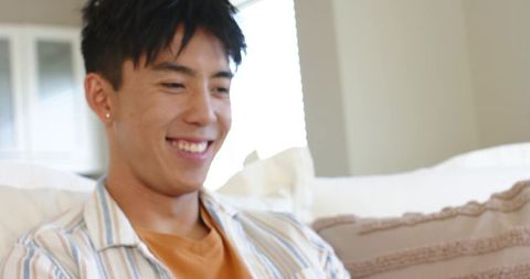 Smiling young man relaxing on sofa in bright minimalist living room casual lifestyle