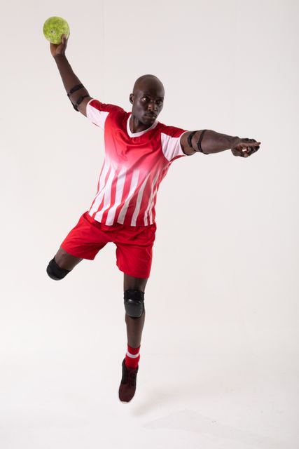 Confident african american young male athlete throwing handball on white background with copy space. unaltered, sport, competition and game concept.