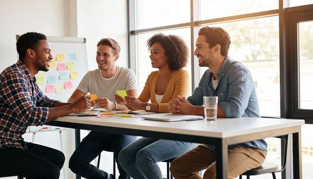 Diverse team brainstorming around table sharing sticky notes in bright modern office