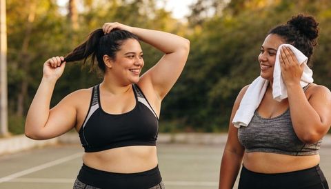 Two women smiling and cooling down on outdoor court during golden hour