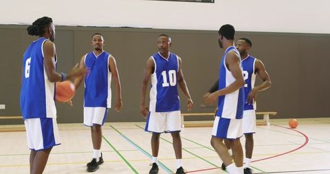 Male basketball team huddling on court planning play after dribble — teamwork strategy