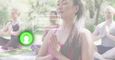 Young woman practicing mindful meditation outdoors in sunlit group yoga class