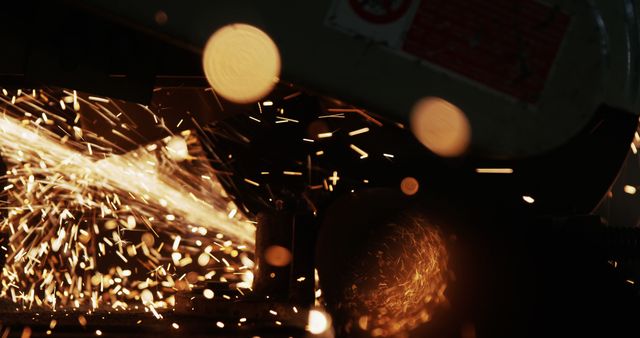 Close-up showing an industrial worker operating a grinder with flying sparks, highlighting the intensity and precision required in metalworking and manufacturing. This can be used in articles about manufacturing processes, safety in industrial environments, or for illustrating the kind of work performed in metal workshops.