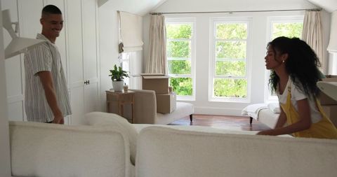 Couple unpacking boxes in bright living room while moving