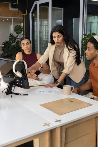 Multicultural team collaborating over charts and monitor in modern coworking office
