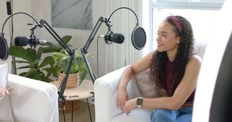 African american woman hosting cozy home podcast interview with dual boom microphones