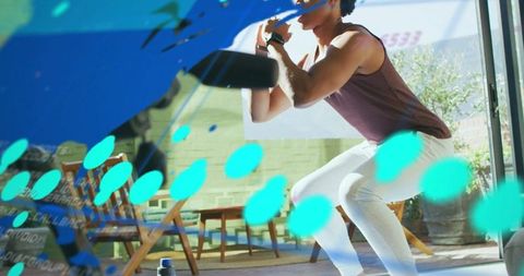Athlete squatting with kettlebell in sunlit studio with glass wall and vibrant blue overlay