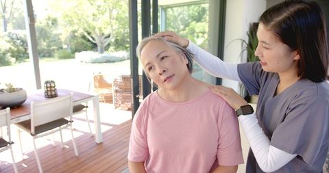 Physiotherapist Assists Senior Woman at Home with Neck Exercises