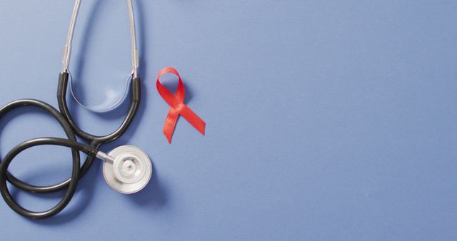Image of stethoscope and red blood cancer ribbon on blue background. medical and healthcare awareness support campaign symbol for blood cancer.