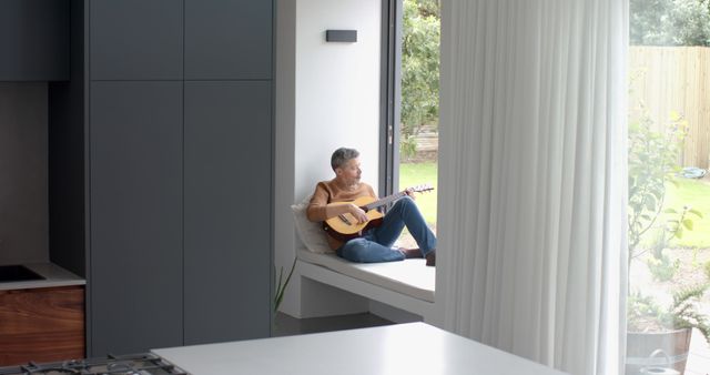 Man Enjoying Relaxing Moment while Playing Guitar in Modern Home - Download Free Stock Images Pikwizard.com