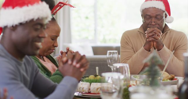 African american family praying before christmas dinner. Spending quality time with family at christmas concept.