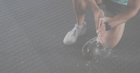 Kettlebell chalk routine kneeling athlete preparing hands over weight on rubber floor