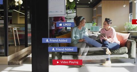 Coworkers collaborating on sofa in modern open-plan office with social media notifications