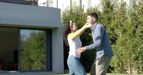 Diverse Couple Embracing Outside Modern House