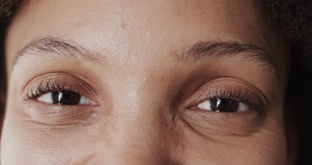 Close-up shot focusing on the brown eyes of a person. This can be used in blogs and articles discussing emotional expressions, psychology, the beauty of human facial features or personal stories. It can also be utilized in advertisements promoting self-care and eye care products.