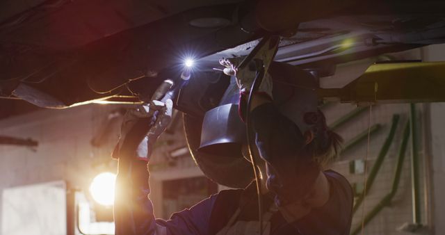 Mechanic Welding Under Vehicle in Workshop with Protective Gear - Download Free Stock Images Pikwizard.com