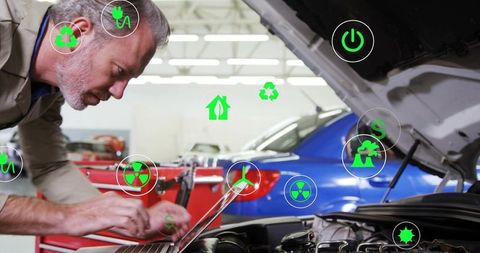 Senior mechanic using laptop for automotive diagnostics and sustainability checks
