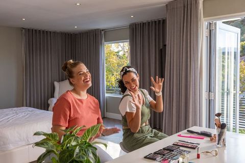 Women enjoying makeup in modern bedroom with natural light