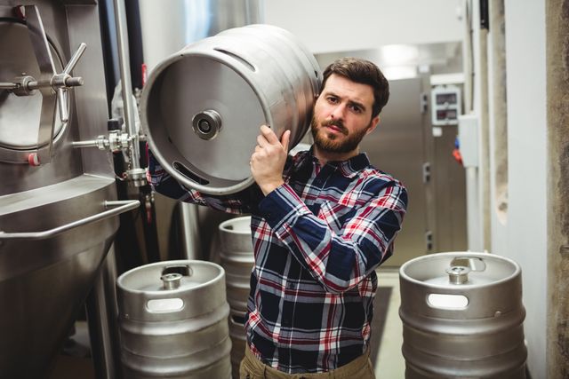 Portrait of manufacturer carrying keg in brewery