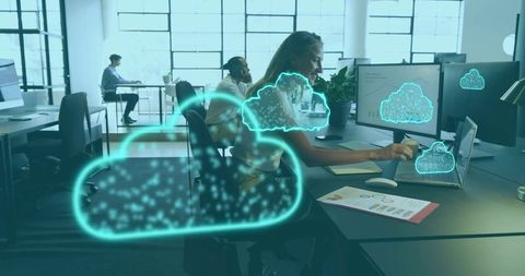 Mid-career woman working on laptop with dual monitors and neon cloud computing overlays