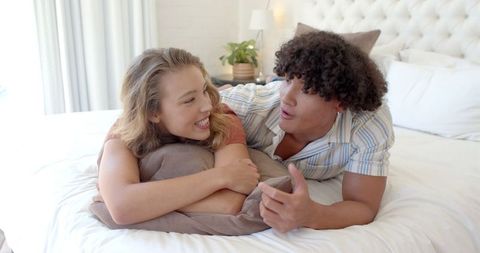 Happy couple relaxing on cozy bed in bright bedroom