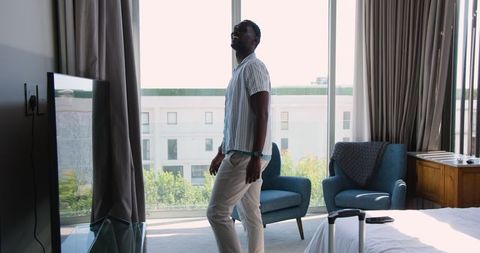 Man in hotel room enjoying urban view by large window