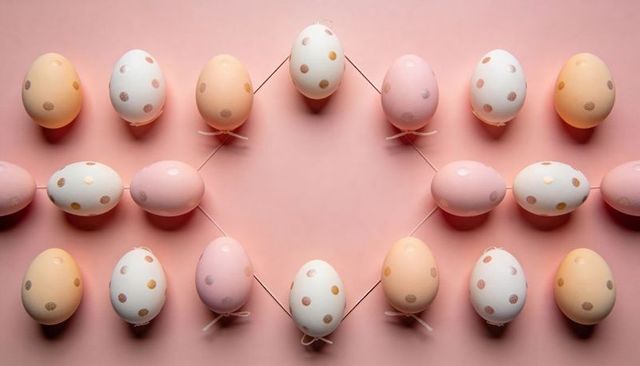 Pastel polka dot easter eggs arranging in symmetrical diamond on blush pink surface