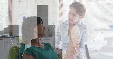 Dental clinician holding mirror during patient consultation with charts overlay