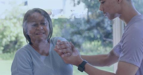 Smiling senior woman receiving hand support from caregiver with dotted world map overlay