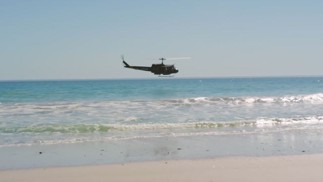 Helicopter flying low over the ocean near a sandy beach. Can be used for coastal activities, aviation themes, or travel advertisements. Ideal for demonstrating adventure, safety, or exploration.