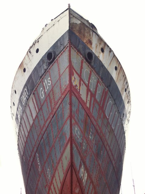 Capturing detailed view of historic ship's bow showing extensive rust and weathering. Useful for illustrations on maritime history, shipbuilding techniques, industrial decay, or rust texture references in art and design. Suitable for educational content, documentaries, or nautical-themed projects.