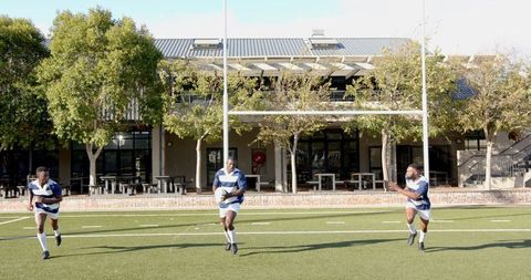 Rugby players passing ball underneath goalpost in action