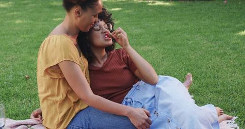 Women Sharing Cherry on Picnic Blanket in Park, Intimate Lesbian Couple Relaxing Outdoors