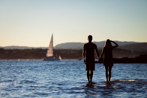 Romantic Silhouette of Couple Walking in Water at Sunset