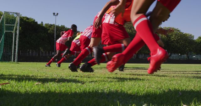 Youth soccer players kicking off soccer practice in motion, showcasing dynamic action and teamwork in red uniforms. Useful for sports promotions, youth training programs, teamwork concepts, physical activity campaigns, and sports event advertisements.