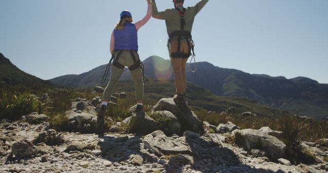 Caucasian couple wearing helmets, holding hands up and trekking in mountains, copy space. Relationship, trekking, active lifestyle, safety and nature concept, unaltered.