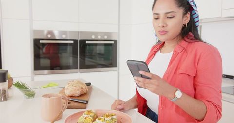 Woman in Kitchen with Smartphone Over Avocado Toast and Coffee