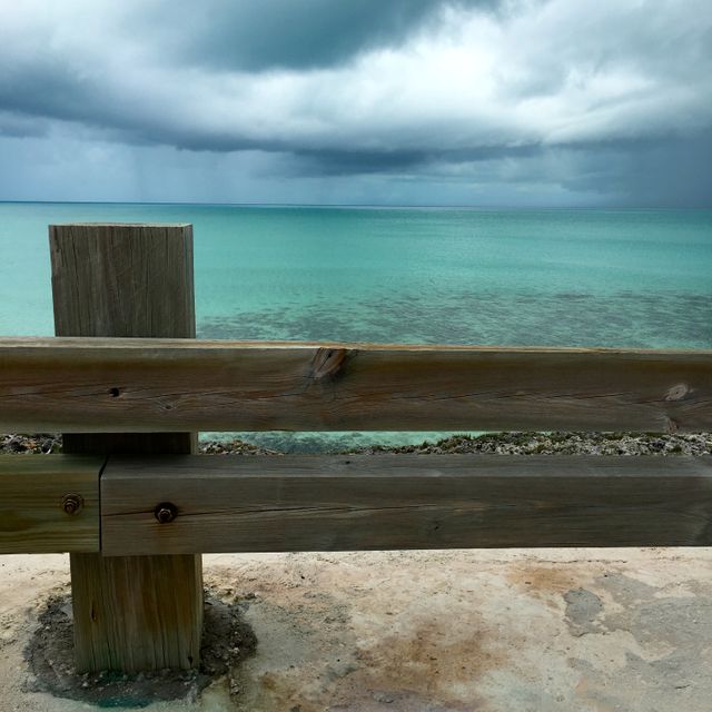 Wooden Fence Overlooking Calm Turquoise Sea Under Cloudy Sky - Download Free Stock Photos Pikwizard.com